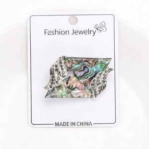 Detailed close-up of a vintage quadrilateral abalone shell brooch with grey rhinestones