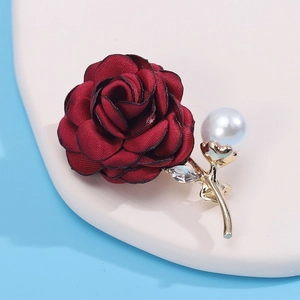 Detailed view of red fabric rose brooch with gold metal stem, large pearl and crystal