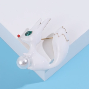 Détail de la broche renard en émail blanc avec yeux en pierre verte et perle centrale