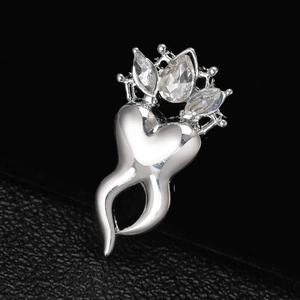 Macro view of crown-shaped tooth brooch with silver plating and white zircon inlay