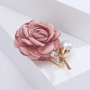 Detailed macro of pink fabric camellia brooch with white pearl and rhinestone stem accent