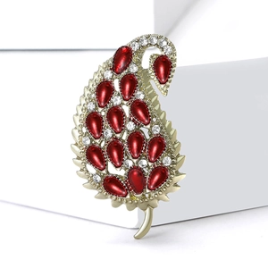 Elegant gold leaf brooch with deep red enamel and white rhinestones on jewelry box