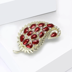 Macro view of gold leaf brooch with red teardrop stones and sparkling white rhinestones