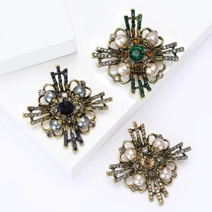 Baroque pearl brooch pins in gold, blue, and green finishes with intricate gemstones