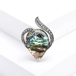Detailed macro view of an abalone shell teardrop brooch with vintage silver metal frame