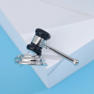 Detailed close-up of a silver-toned gavel brooch with black enamel on geometric stands