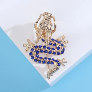 Macro shot of gold-plated dragon brooch with blue rhinestones on a white pedestal