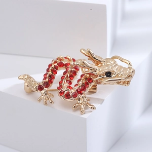 Detail of a golden dragon brooch with red rhinestones and relief texture on white background