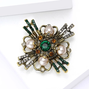 Macro shot of Baroque pearl brooch with vintage gold finish and green gemstone detailing