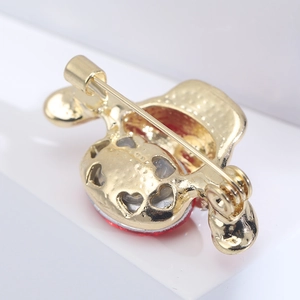 Macro shot of gold-plated brooch back featuring heart cutouts and safety pin closure