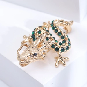 Exquisite gold-plated Chinese dragon brooch with sparkling green rhinestones on a white base