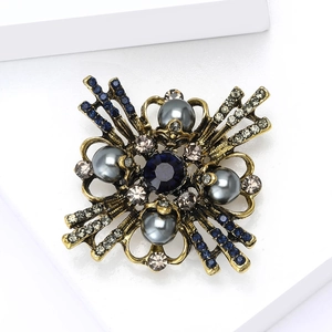 Macro view of vintage baroque brooch with dark blue crystal and grey pearls on gold base