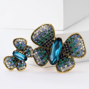 Macro detail of vintage gold butterfly brooch with blue rhinestones on white display