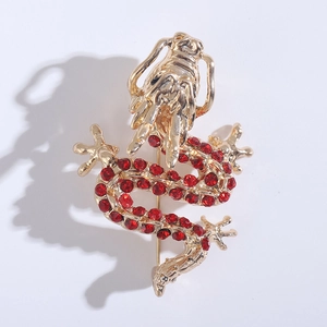 Detailed view of golden dragon brooch with sparkling red rhinestones on white background