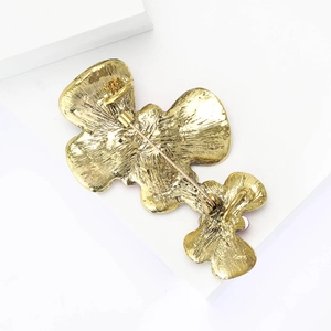 Detail view of the back of a golden flower brooch with pin clasp and textured metal
