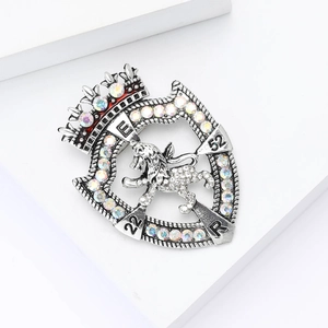 Vintage silver shield brooch with lion crest, crown and rhinestones on white display