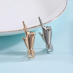 Macro shot of silver and gold hip-hop hand gesture pins with zircon stones and polished finish