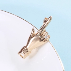 Detail of creative gold hand gesture pendant with clear cubic zirconia on ceramic edge