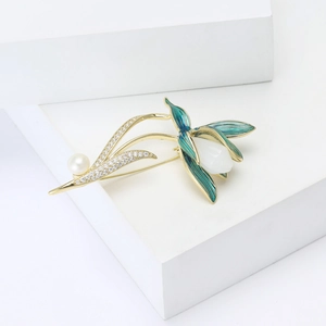 Broche magnolia élégante avec finition dorée, feuilles en émail vert et perle blanche