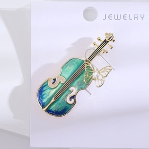 Détail macro d'une broche violon avec corps en émail vert et papillon doré ciselé