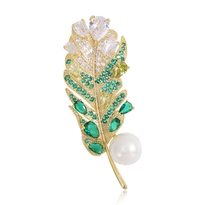 Vue détaillée d'une broche plume avec cristaux verts et perle blanche ronde