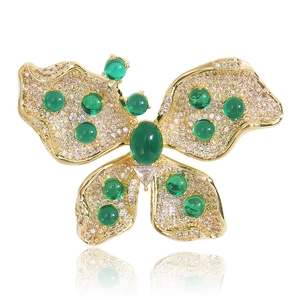 Détail macro d'une élégante broche papillon en métal doré avec des pierres précieuses vertes