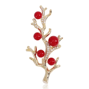 Détail de la broche en forme de branche avec zircons blancs et cinq perles rouges
