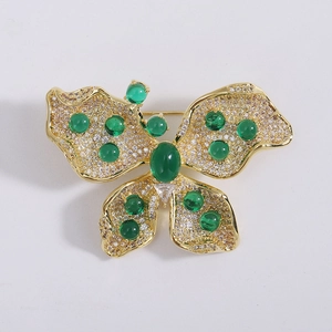 Détail d'une broche papillon dorée avec des pierres vertes et incrustation de zircon
