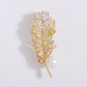 Détail de la broche plume dorée avec gemmes en cristal et une perle blanche ronde