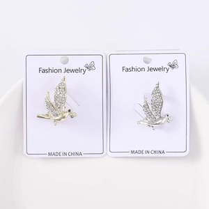 Détail de broches oiseaux en or et argent avec incrustation de strass brillants