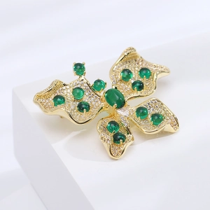 Vue détaillée d'une broche papillon en or avec zircons et pierres précieuses vertes