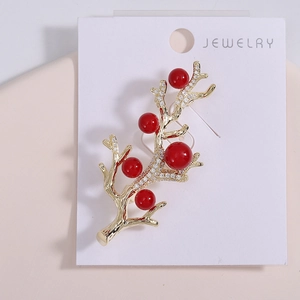 Détail d'une broche branche dorée avec perles rouges et oxydes de zirconium brillants