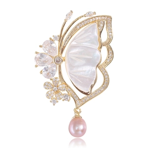 Detailed butterfly brooch with mother of pearl wings, gold plating and purple pearl drop
