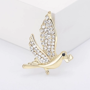 Broche pigeon dorée avec strass et détail d'enveloppe sur bloc blanc