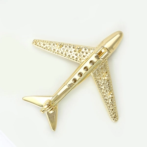 Detail showing the polished gold airplane brooch with wings featuring granular texture