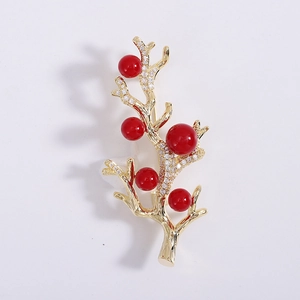 Détail macro d'une broche branche de corail dorée avec perles rouges et zirconiums