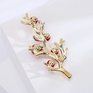 Détail de la broche branche dorée avec perles rouges et fermoir de sécurité rotatif