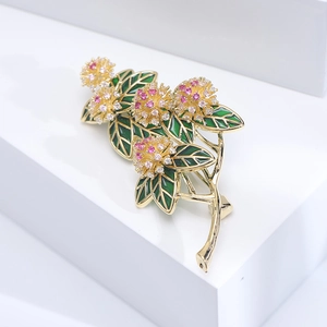 Macro shot of floral brooch with green enamel leaves and pink zircon flower clusters