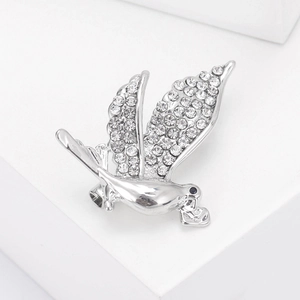 Détail de la broche pigeon argentée avec strass blancs et pendentif en forme de cœur