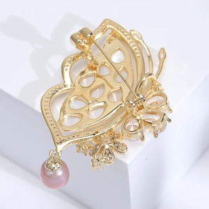 Close-up of golden butterfly brooch back with pink pearl drop and clasp detail