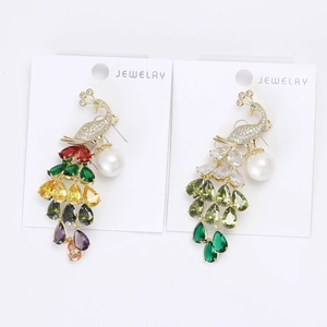 Macro view showing two peacock brooches with colorful crystals and white round pearls