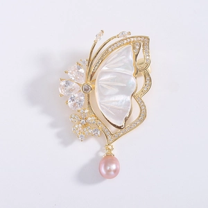 Macro shot of a butterfly brooch featuring white mother of pearl and a pink pearl drop