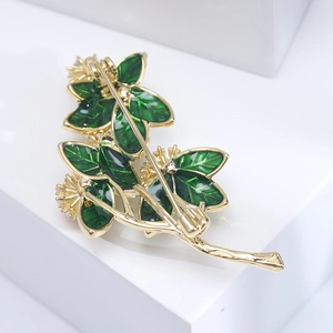 Detail showing back view of gold flower brooch with safety pin clasp and green enamel