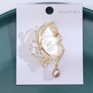Macro detail of butterfly brooch with shell inlay, zircon stones and pink pearl drop