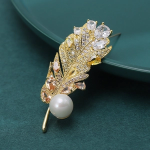 Broche élégante en forme de plume dorée avec zircons brillants et une perle blanche