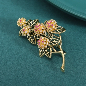 Elegant floral branch brooch with pink and white cubic zirconia on green velvet background