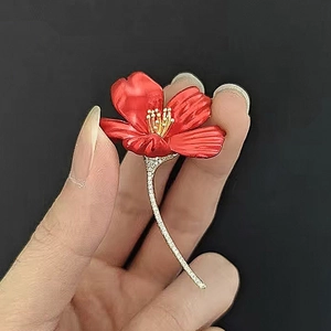 Detailed view of red hibiscus flower brooch with enamel petals and sparkling zircons