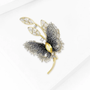 Élégante broche papillon avec pierre jaune et tissu texturé gris sur cadre doré