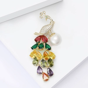 Detailed view of peacock brooch with colorful gemstones and white pearl on a white stand
