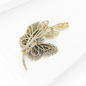 Vue détaillée de la broche papillon dorée avec texture métallique évidée et épingle de fixation
